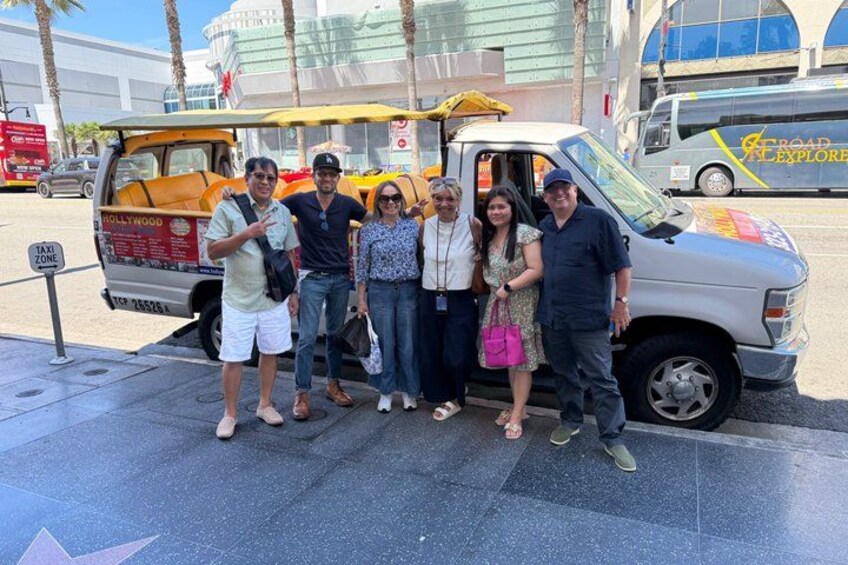 A group of people posing in front of a van with a 'Hollywood' sign. 2