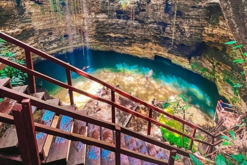 Una escalera que lleva a una cueva con una piscina azul cristalina al final. 5