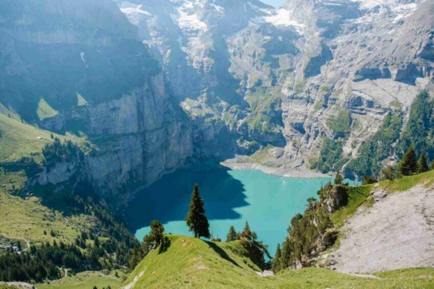 A mountainous landscape with a turquoise lake surrounded by cliffs and greenery. 3