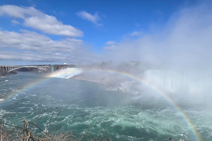 A waterfall with a rainbow, a bridge, and a misty atmosphere. 1