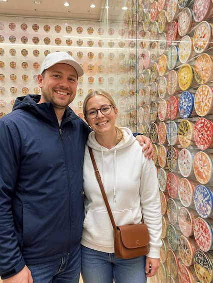 Two people standing in front of a wall with colorful circular patterns. 1