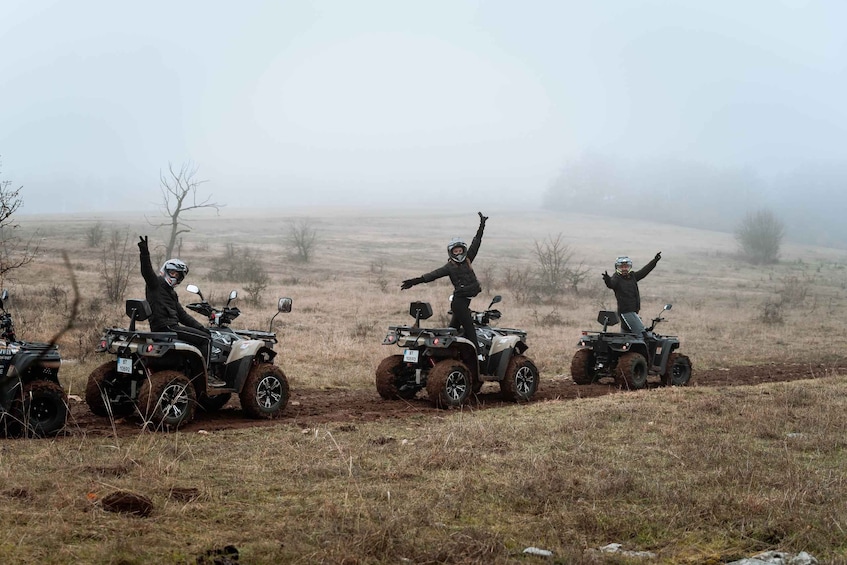 Three people on ATVs in a foggy field. 4