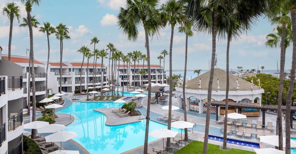 A resort with a large pool surrounded by palm trees and hotel buildings. 1