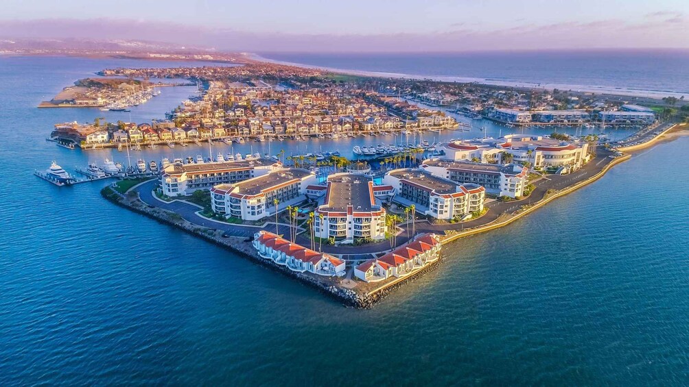 An aerial view of a coastal town with a marina, residential buildings, and a prominent waterfront promenade. 5