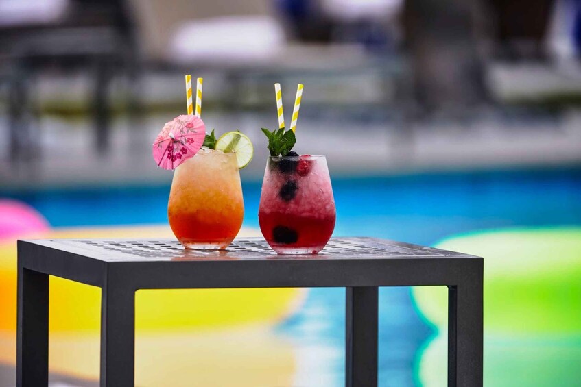 Two colorful cocktails on a table by a pool. 3