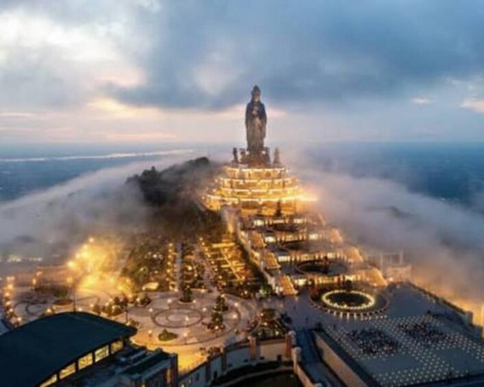 A large, illuminated statue on a hilltop with a cityscape below. 3