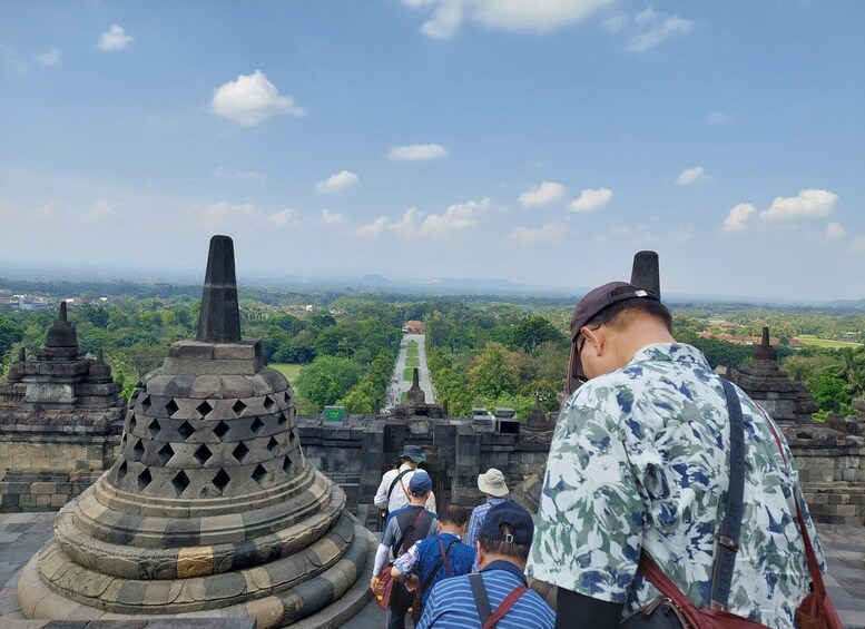 A group of people at a historical site with stone structures and a view of a distant landscape. 1