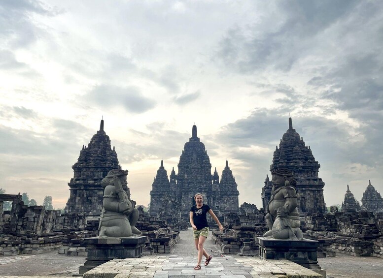 A person standing in front of ancient stone structures with multiple towers. 3