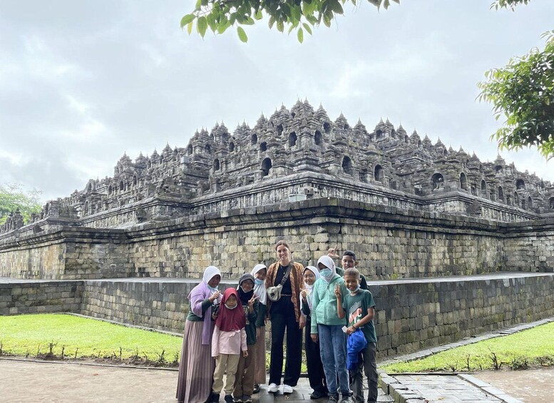 A group of people standing in front of a large, ornate temple with multiple tiers and intricate stone carvings. 2
