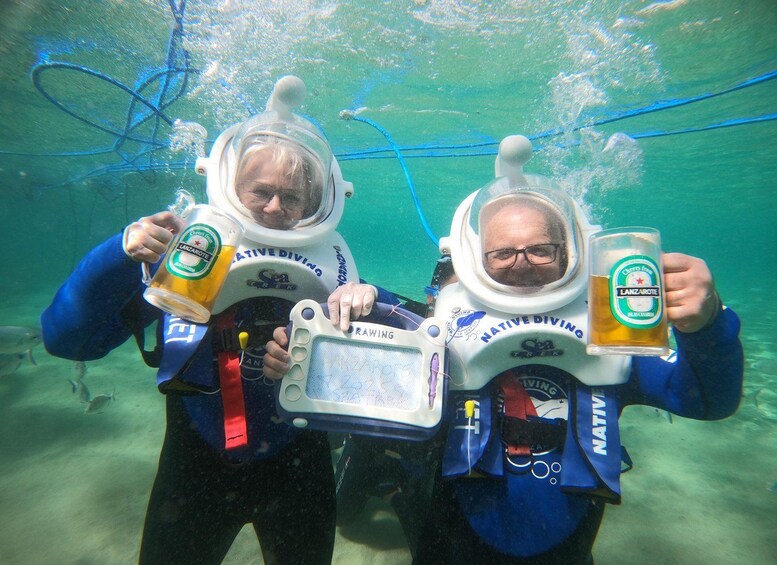 Two people underwater wearing diving helmets and holding beer mugs. 4