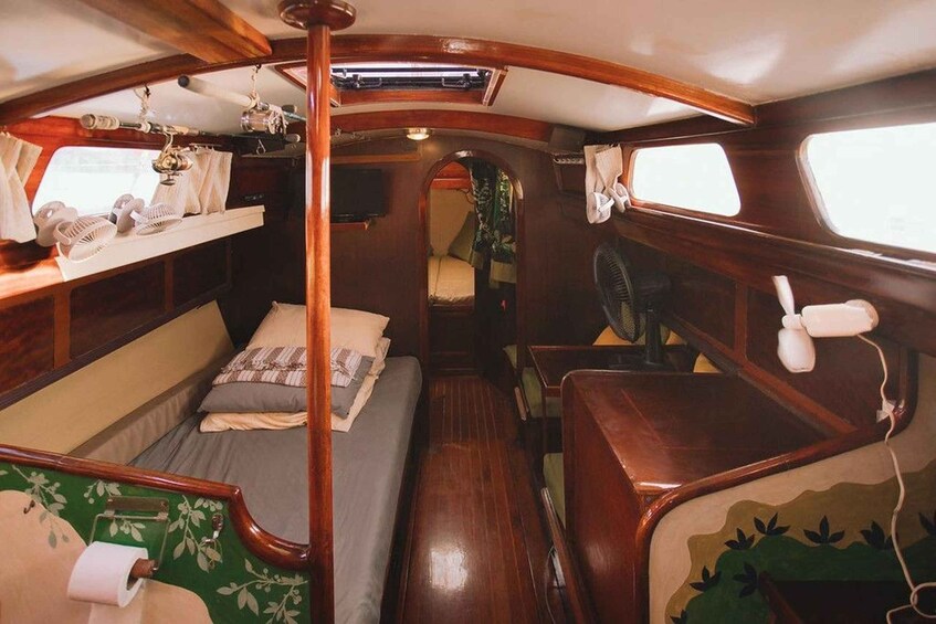 A cozy interior with wooden walls, a bunk bed, a small table, and a fan. 4