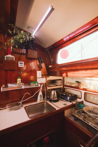 A compact kitchen with wooden cabinets, a sink, a stove, and a window. 3