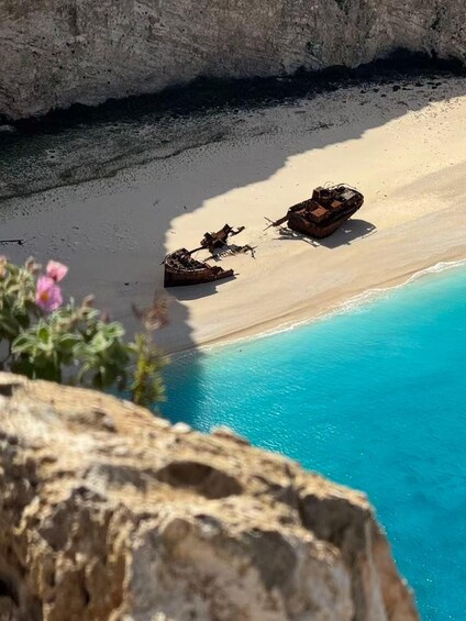 A beach with two rusted boats and a clear blue sea. 1