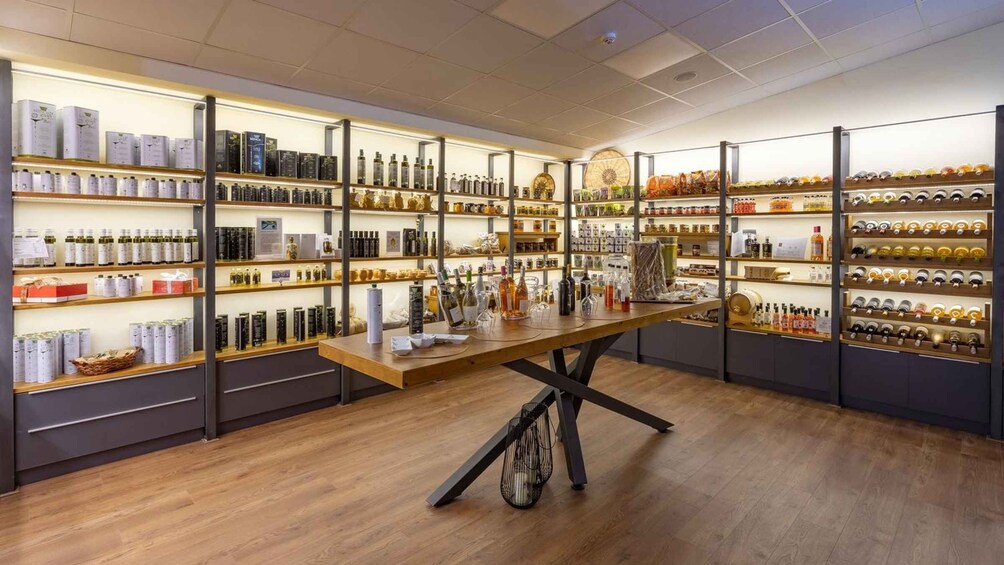 En velbelyst butik med hylder fyldt med forskellige flasker og krukker, et træbord i midten og et mønstret loft. 5