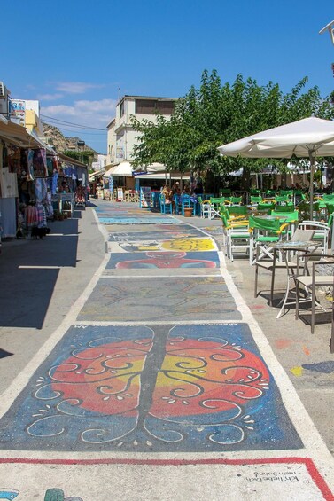 A street with colorful pavement art, outdoor seating, and shops. 5