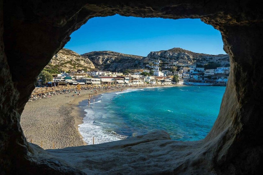 A coastal town with buildings on a hillside, a beach, and clear blue waters. 3