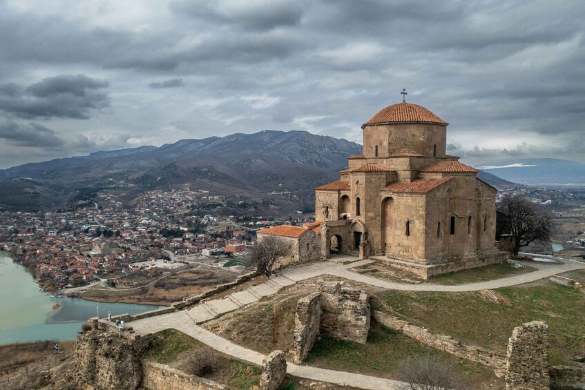 Eine historische Kirche mit rotem Ziegeldach, eingebettet in eine gebirgige Landschaft und einer Flusslandschaft. 3