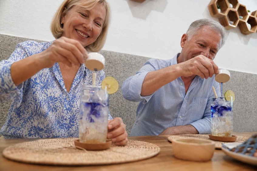 Two people sitting at a table with drinks and a woven placemat. 4