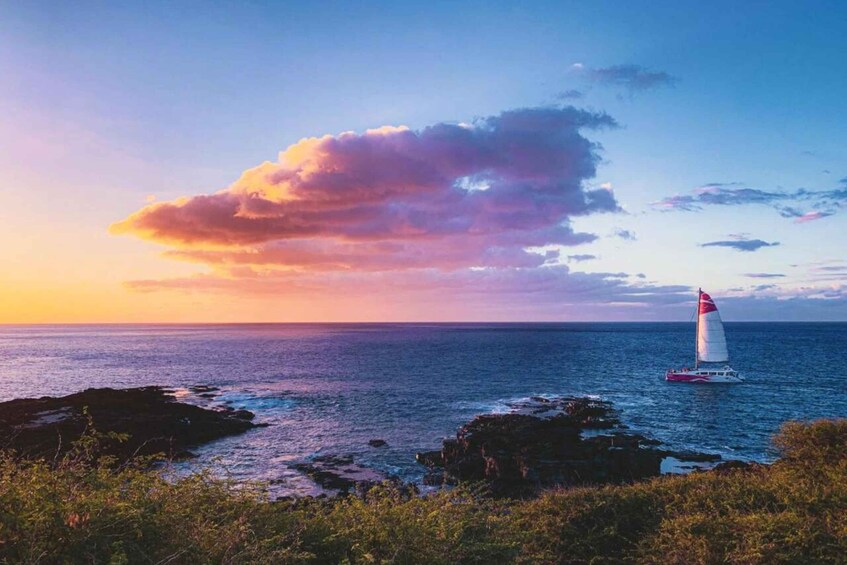 Una barca a vela su un mare calmo, con un cielo al tramonto e una costa rocciosa. 1