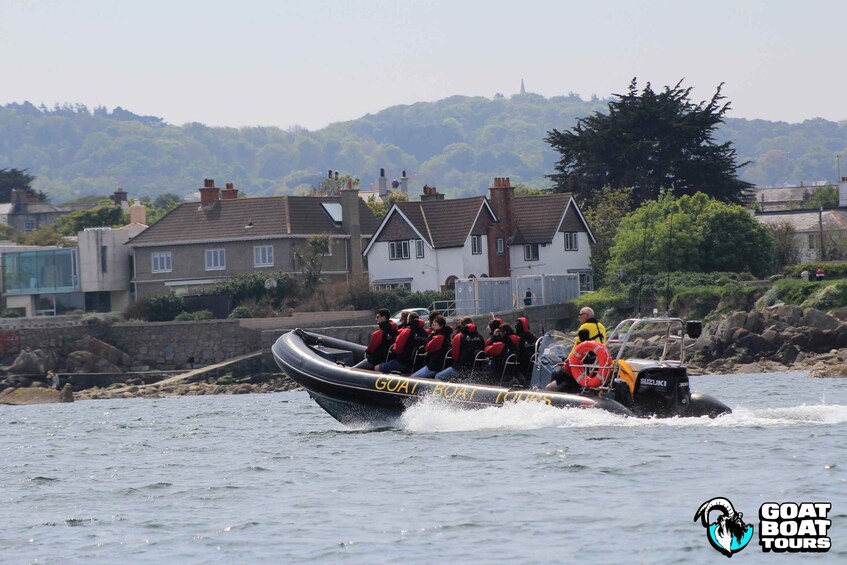 A boat tour with passengers wearing life jackets, a guide, and a small motorboat. 1