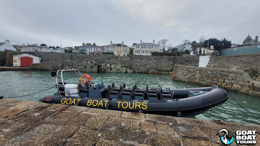 A goaf boat docked at a stone pier with a stone wall and houses in the background. 5