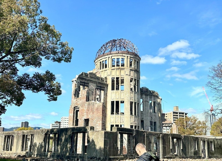 Un bâtiment historique doté d’un dôme et de colonnes, entouré d’arbres et de bâtiments modernes. 1