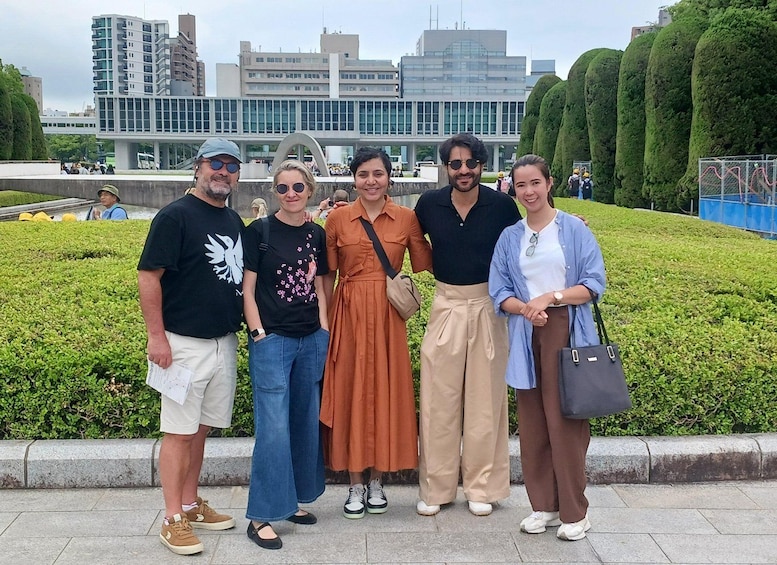 A group of people standing in a landscaped area with a modern building in the background. 5