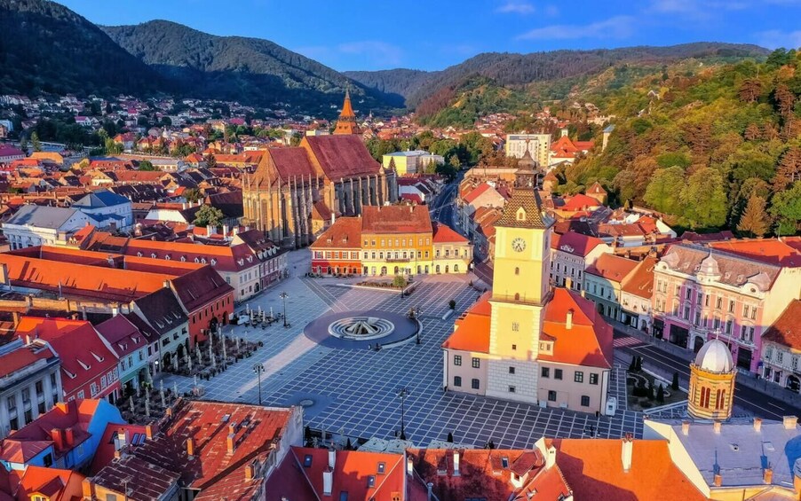 A town square with historic buildings, a prominent clock tower, and surrounding hills. 3