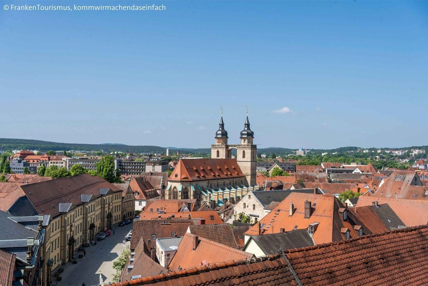 A town with red-tiled roofs, historic buildings, and two prominent towers with spires. 3
