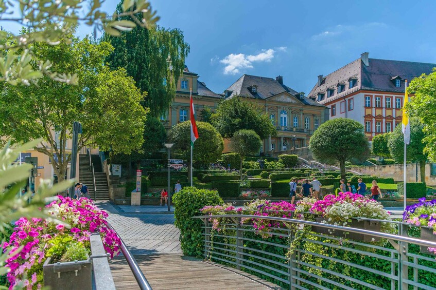 A pedestrian bridge with metal railings, surrounded by vibrant flower beds and a well-maintained garden. 5