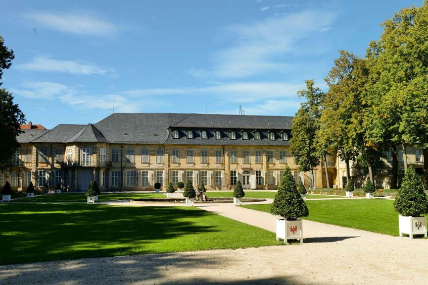 A large, historic building with a symmetrical facade, surrounded by well-manicured lawns and trees. 4