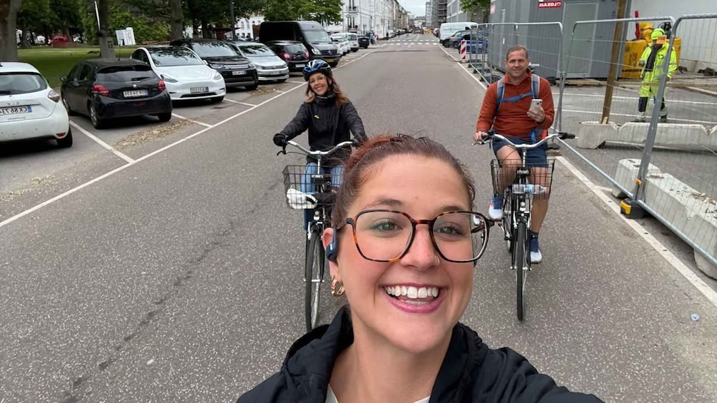 Katu, jonka varrella on parkkeerattuja autoja ja jolla kaksi pyöräilijää ajaa. 3
