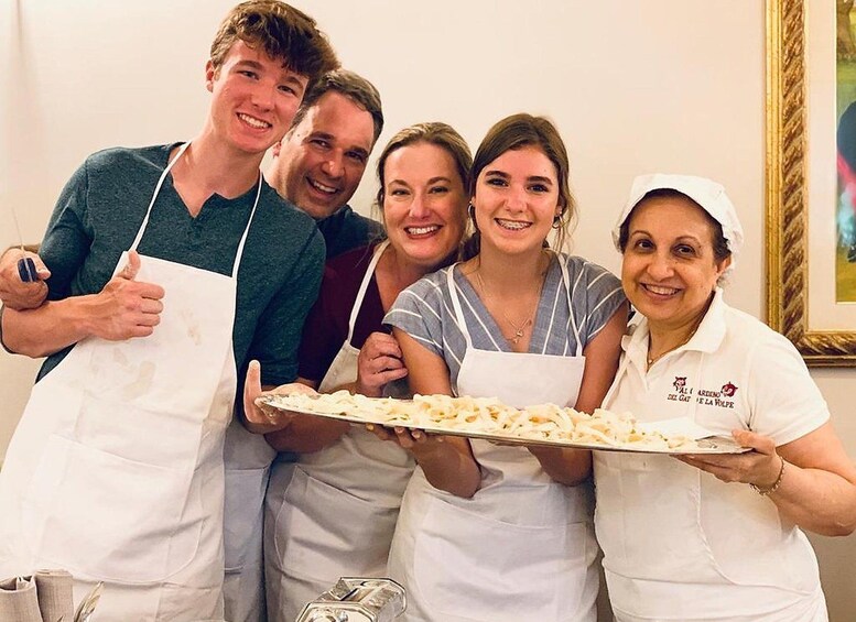 Een groep mensen in witte schorten die een groot dienblad met eten vasthouden. 1
