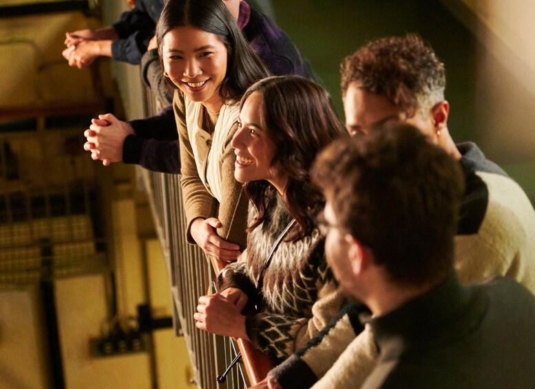 A group of people standing indoors, some holding hands, with a blurred background suggesting an urban setting. 3