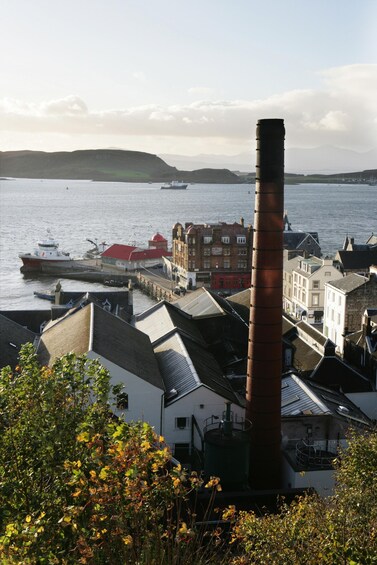 A coastal town with a prominent red chimney, a dock with boats, and a hill in the background. 2