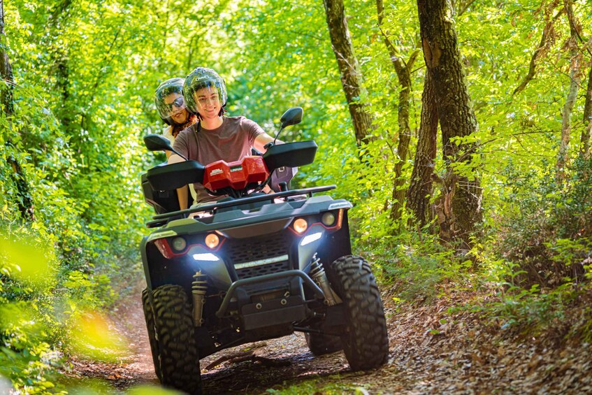 Two people on a four-wheeled vehicle in a forested area. 3