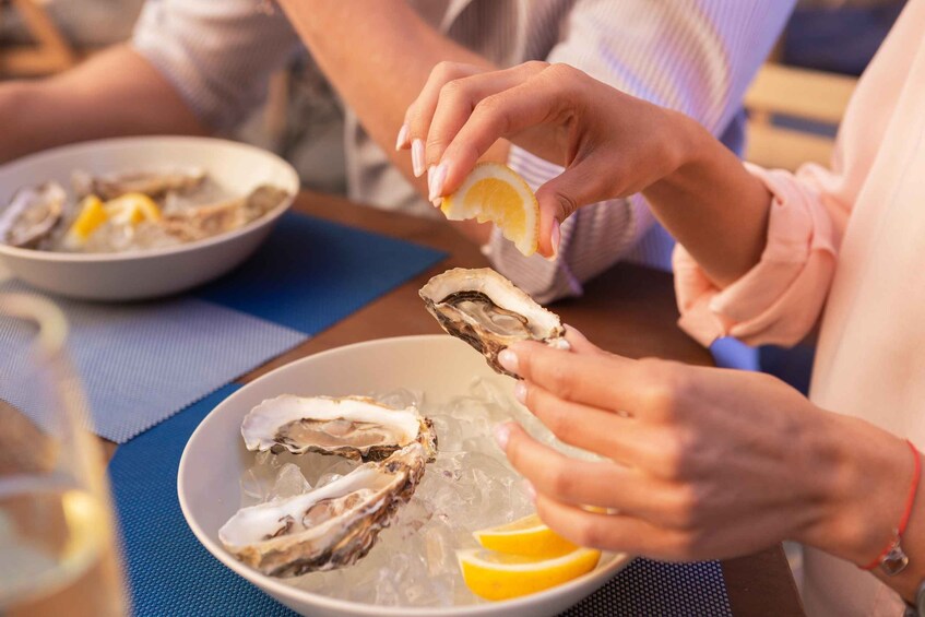 A person holding an oyster with a lemon wedge. 5