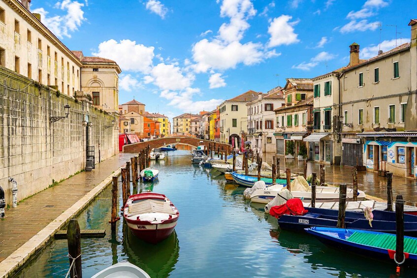 A canal lined with colorful buildings, a bridge, and boats docked along the water. 2