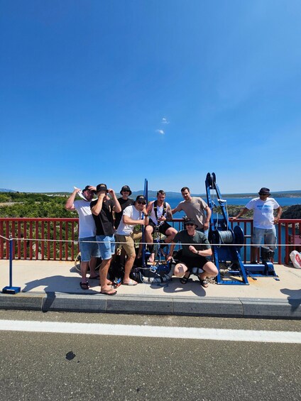 A group of people on a pier with a clear blue sky and a view of the sea. 3