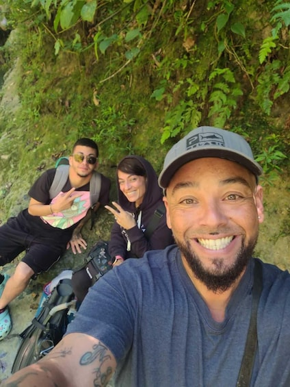 Three people sitting on a trail, surrounded by greenery. 2