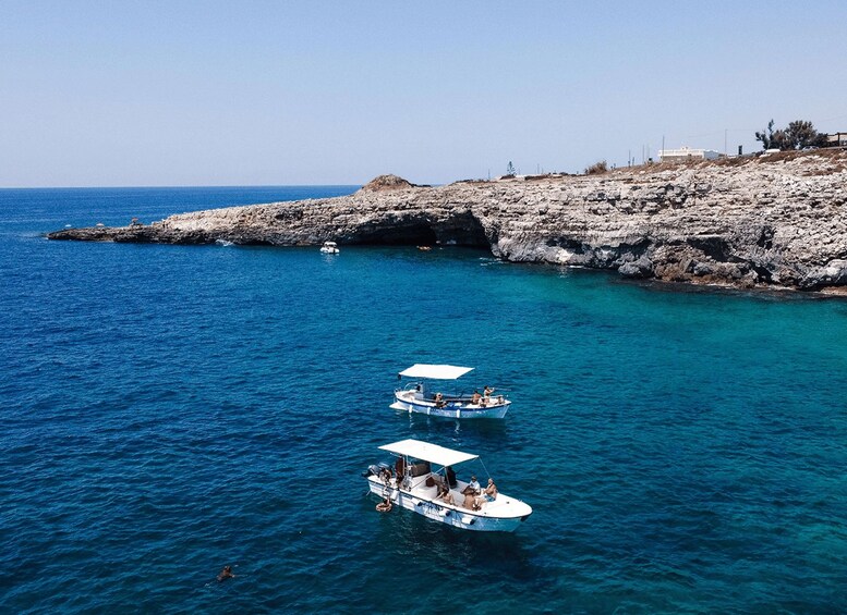 Two boats on a clear blue sea with rocky cliffs in the background. 3