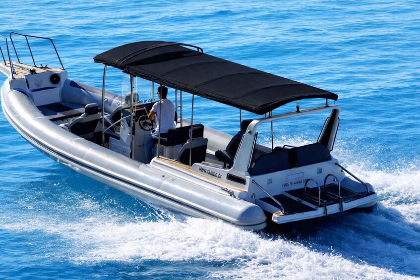 A motorboat with a black canopy, moving through clear blue water. 3