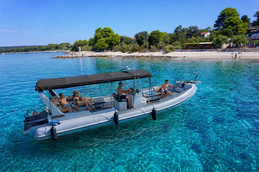 A boat with people on a clear blue sea, surrounded by trees and a sandy beach. 1