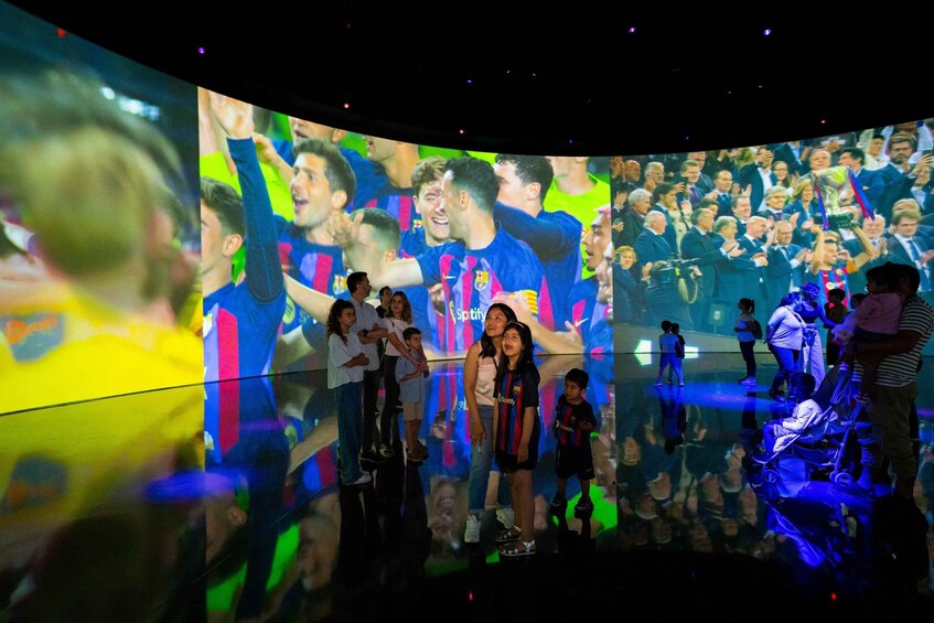 A group of people in front of a large screen displaying a sports event. 4