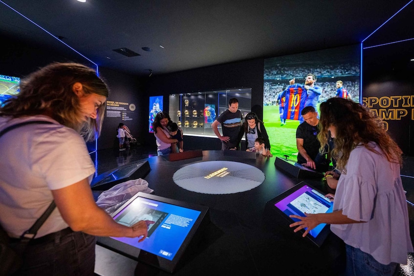 A museum exhibit with interactive displays and a large screen showing a soccer match. 5