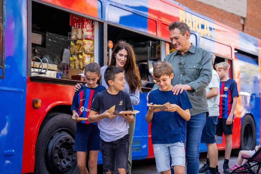 A family of five standing in front of a food truck with a blue and red color scheme. 1