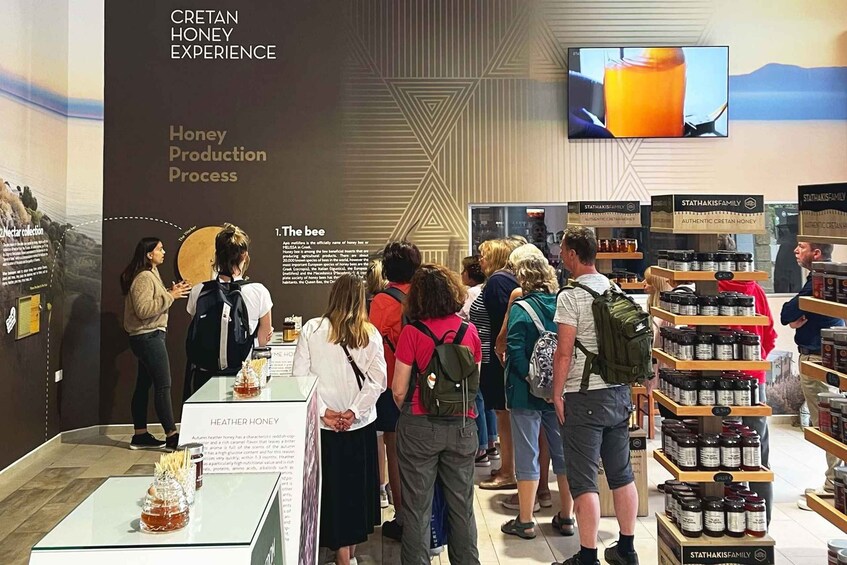 Eine Honigverkostung mit Menschen, die um Tische stehen, und einer Ausstellung mit Honiggläsern. 5