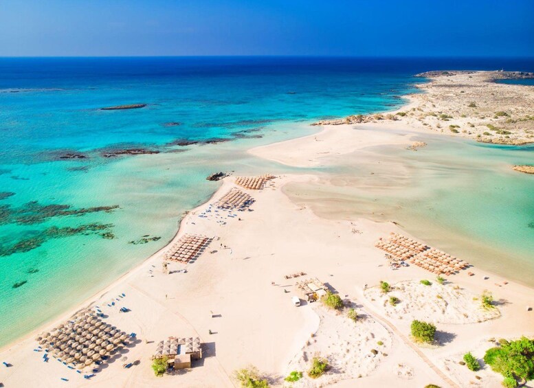 Ein Strand mit klarem türkisblauem Wasser, sandigem Ufer und vereinzelten Palmen. 1