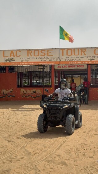 A person riding an ATV in front of a building with a sign that reads 'LAC ROSE TOUR'. 3