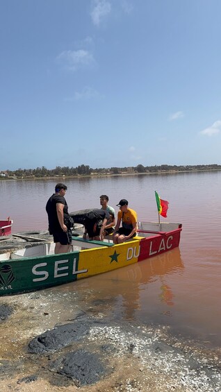 A colorful boat with people on it, a flag, and a calm body of water. 5